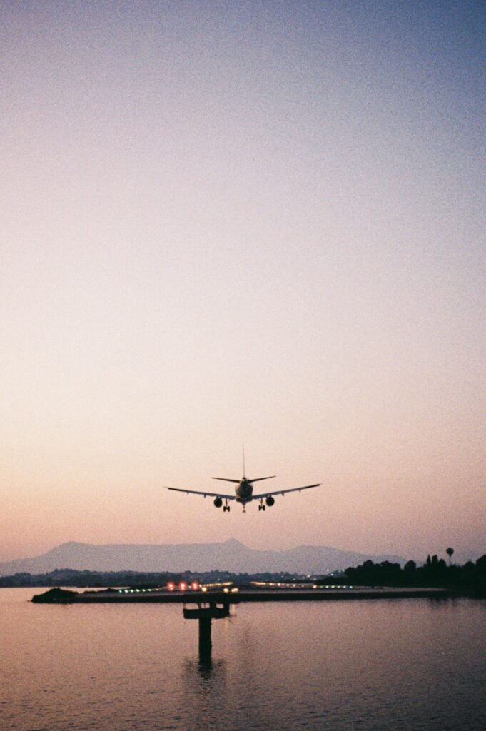 Airplane landing over the water at sunset