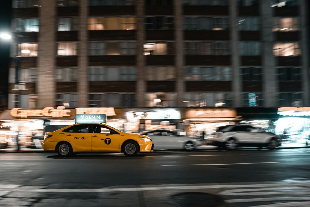 Yellow taxi cab driving on a city street at night